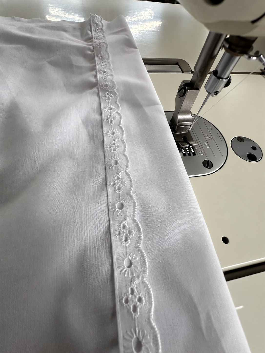 Detalle de encaje blanco junto a nuestra máquina de coser